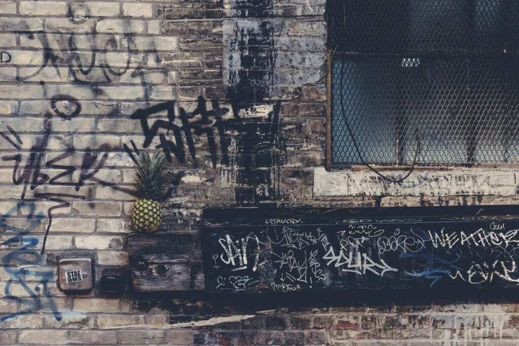 Grunge-style graffiti on an urban brick wall featuring a pineapple, evoking gritty street art vibes.